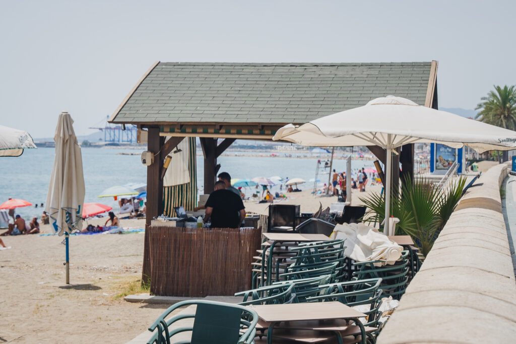 Familia con niños comiendo en una mesa de Chiringuito Picasso con la playa de La Malagueta de fondo
