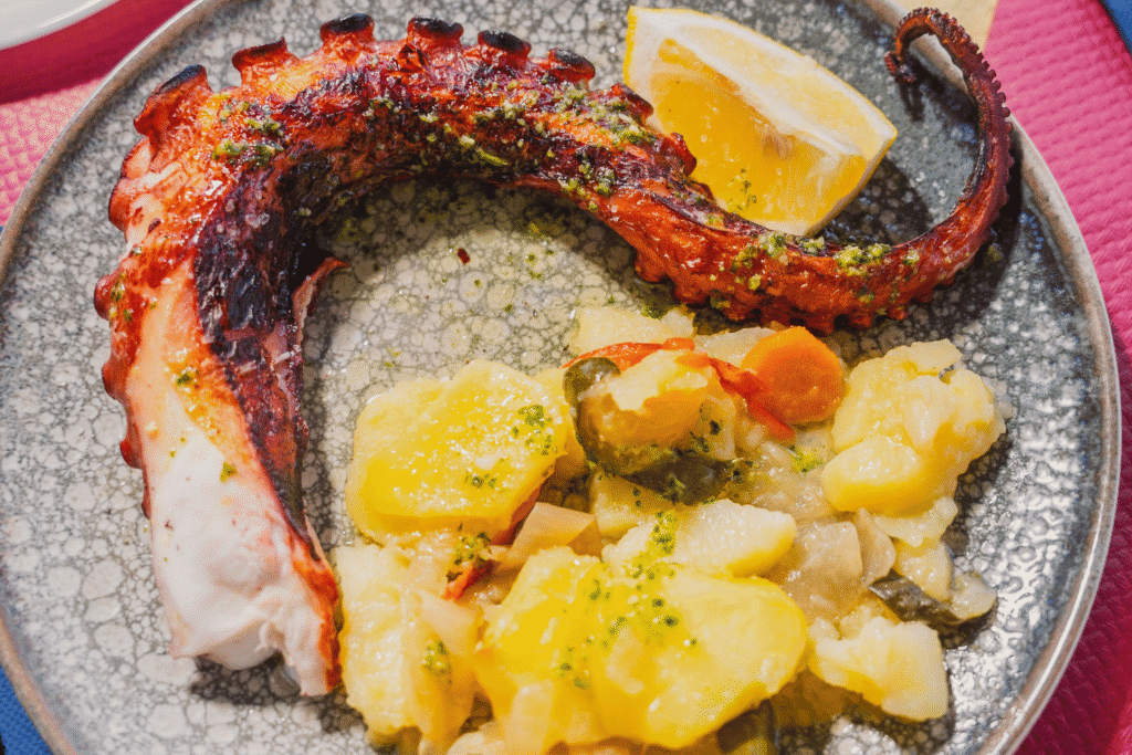 Primer plano de espetos de sardinas y plato de pescaíto frito en una mesa de Chiringuito Picasso en Málaga